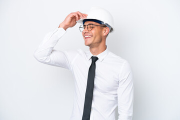 Young architect caucasian man with helmet and holding blueprints isolated on white background smiling a lot