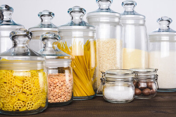Various products, pasta, nuts, rice in glass jars on the white background.