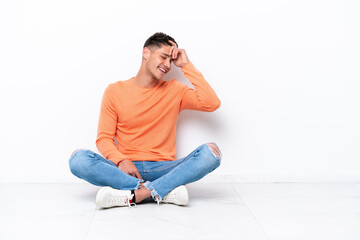Young man sitting on the floor isolated on white background laughing