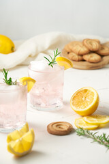 Summer refreshing drinks. Pink lemonade with juicy lemon slices, rosemary and butter tea cookies. Colorful kitchen scene, bright background. 