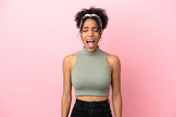 Young latin woman isolated on pink background shouting to the front with mouth wide open