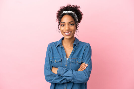 Young latin woman isolated on pink background with arms crossed and looking forward
