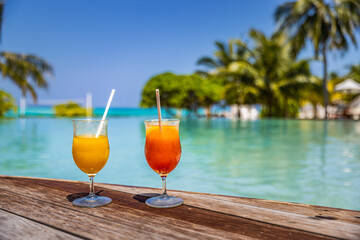 Perfect summer beach resort, poolside with two colorful cocktails. Tropical swimming pool, exotic summer vacation. Chairs, umbrella blurred palm tree leaves, amazing landscape. Freedom relax holiday