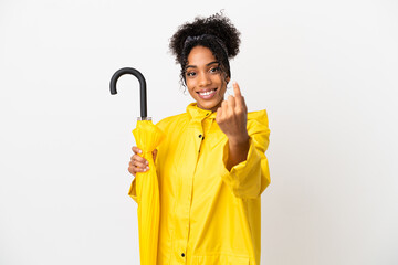 Young woman with rainproof coat and umbrella isolated on white background doing coming gesture