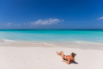 Fototapeta na wymiar Young sexy woman relax on the beach. Perfect tropical island, beach shore, with turquoise ocean lagoon. Bikini, long legs, sunglasses enjoying summer vacation. Carefree woman beach portrait, leisure 