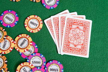 Four cards sit on a poker table face down next to a pile of high-value poker chips. 