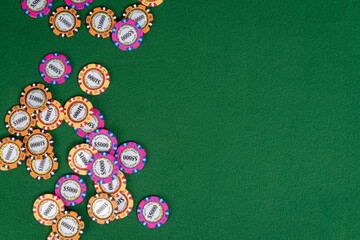 A pile of high-value poker chips sits on a poker table with lots of copy space on the right. 