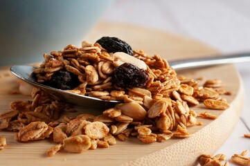 Granola on a spoon and over a cutting board with a blue blurry bowl in the background. Macro photography