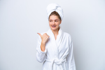 Teenager Russian girl in a bathrobe isolated on white background pointing to the side to present a product