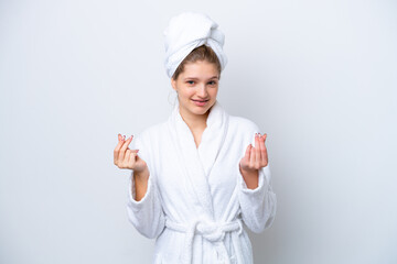 Teenager Russian girl in a bathrobe isolated on white background making money gesture