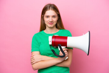 Teenager Russian girl isolated on pink background holding a megaphone and smiling