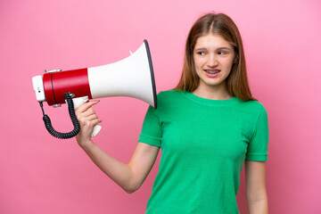 Teenager Russian girl isolated on pink background holding a megaphone with stressed expression