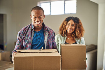 Time to start packing. Portrait of a cheerful young couple carrying boxes together to move into their new home inside during the day.
