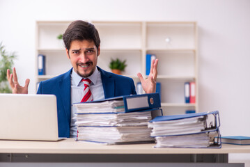 Obraz premium Young male employee unhappy with excessive work in the office