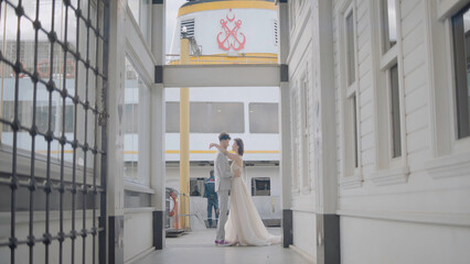 Newlyweds on background of pier. Action. Beautiful newlyweds pose between city buildings. Stylish newlyweds hug on background of city pier in cloudy weather