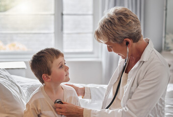 Fototapeta premium Take a deep breath for me. Shot of a doctor examine a little boy with a stethoscope in bed at home.