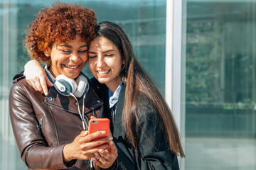 girls smiling in the street looking at the mobile phone
