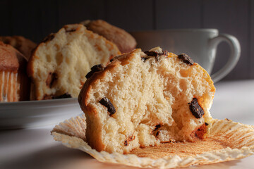 Muffins with chocolate chip on a white plate with a white cup of coffee in the background.