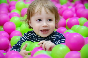 Fototapeta na wymiar portrait of cheerful kid playing with colorful balls, children's day concept, close-up
