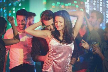 Like no one else is around. Shot of an affectionate young couple dancing on a crowded dance floor in a nightclub.