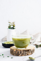 Organic green matcha tea in a cup on a tree trunk on the table. Vertical view