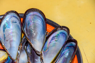 mother-of-pearl shells of black mussels peeled lie in an orange plate