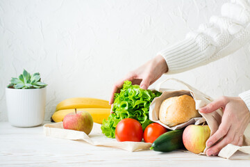 Female hands hold a set of products in eco-friendly textile packaging from delivery on a white table
