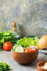 Fresh vegetable bowl with cucumber, tomato and lettuce on the table at home. Vertical view