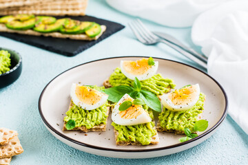 Bruschetta on crispy bread with avocado and boiled egg on a plate.