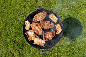 Closeup of a barbeque grill. Appetizing pieces of meat cooking on fire and embers in the backyard.