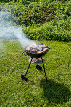 Blue smoke above a coal grill in garden.