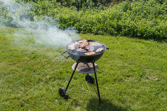 Blue smoke above a coal grill in garden.