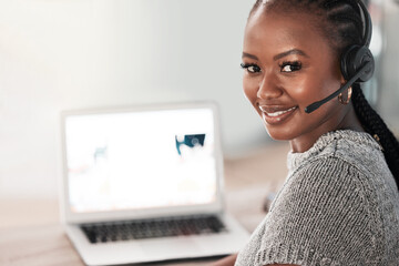 If theres anything you need, Ill be right here. Shot of a young woman using a headset and laptop in...