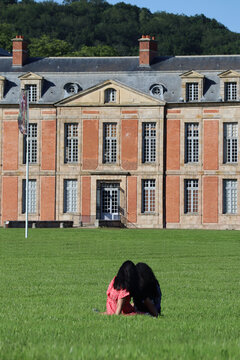 A couple sits on the lawn in front of the Château de Chamarande in the Paris region