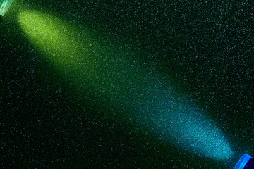 On a dark green background in fine blue grain, oncoming rays of green and blue light