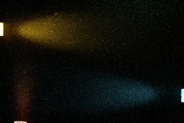 On a dark background in a small multi-colored grain, rays of red yellow and light blue light