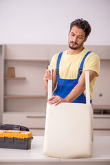 Young male carpenter repairing chair at home