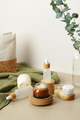 Fototapeta na wymiar Set of SPA natural organic cosmetic products. Jar of moisturizer cream on wooden platform, glass dropper bottles, body brush, loofah. Eco beauty products.
