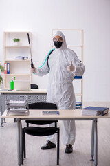 Fototapeta na wymiar Young male contractor disinfecting office during pandemic
