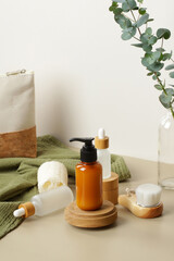 Fototapeta na wymiar Natural SPA cosmetic products set with eucalyptus leaves and green towel. Soap liquid dispenser bottle on wooden platform, glass dropper bottles, body brush, loofah. Eco beauty products.