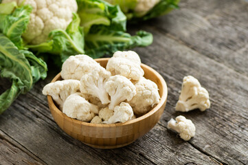 Fresh raw organic cauliflower with leaves on rustic background, uncooked vegetable