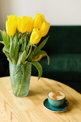 cup of coffee on the table with yellow tulips on the background