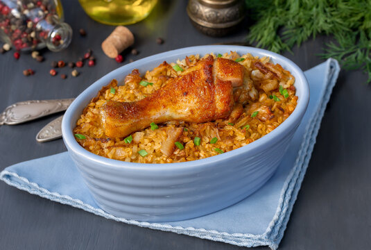 Chicken Bulgur pilaf. Roast chicken drumsticks and bulgur wheat in individual casserole. Horizontal, selective focus, dark background.