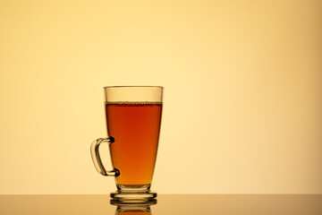 Cup of tea on glass with orange background