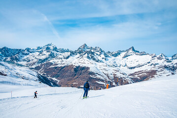 Fototapeta na wymiar Skiers skiing on snow covered slope against mountain range during winter