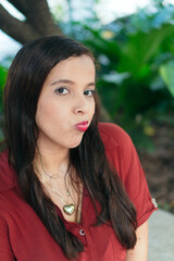 Fototapeta premium Portrait of a young woman in a red blouse in a green park