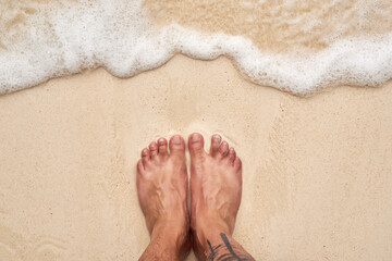 Salty hair and sandy toes. High angle shot of a mans feet at the beach.