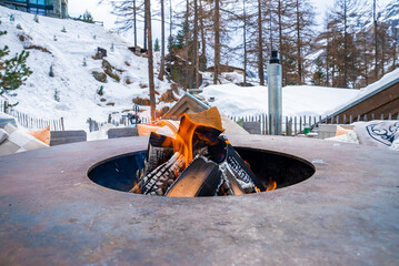 Bonfire in firepit with trees in background at luxurious hotel during winter