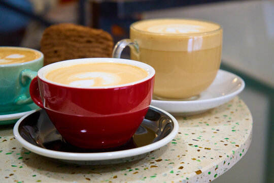 Closeup image of two blue cups of hot latte coffee and cake with latte art on vintage marble table in cafe 