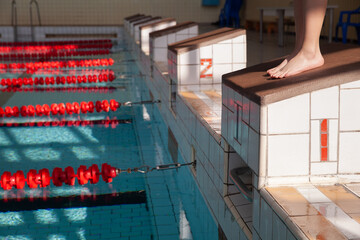 Starting blocks with dividing tracks in the pool. The edge of the room is a sports pool. The child...